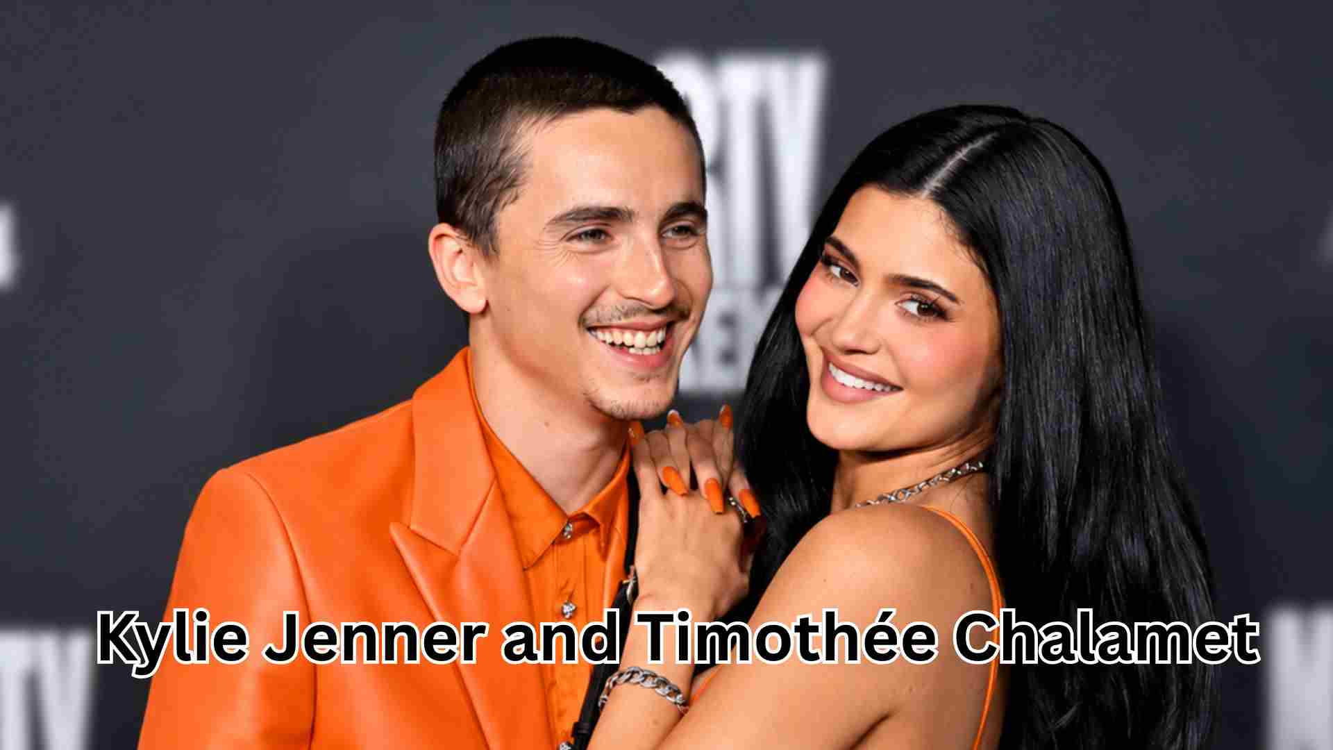 Kylie Jenner and Timothée Chalamet posing together at a red carpet event in matching orange outfits